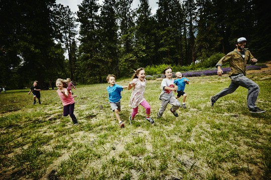 dzieci biegną w lesie z opiekunem